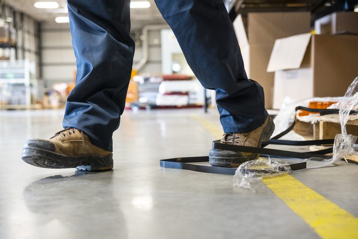 Person stepping on black strapping on a warehouse floor.