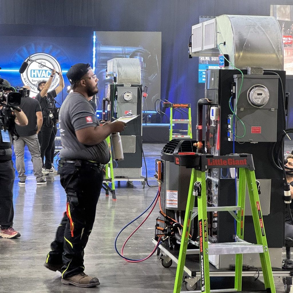 Competitor working on HVAC system installation during the Elite Trades Championship Series, highlighting skilled trades expertise with ductwork and tools.