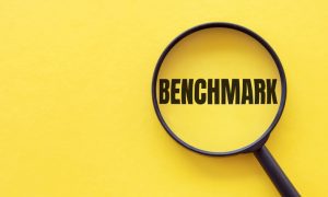 The word BENCHMARK is written on a magnifying glass on a yellow background.